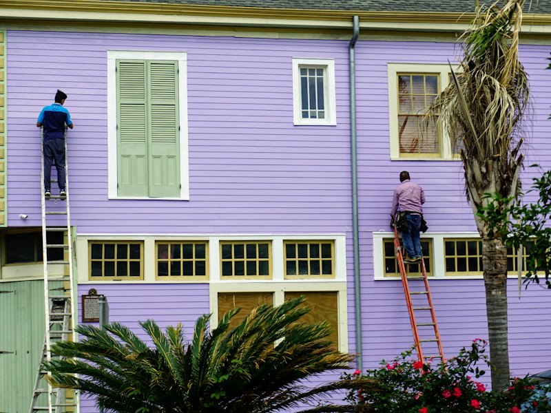 Painters on ladders painting a house