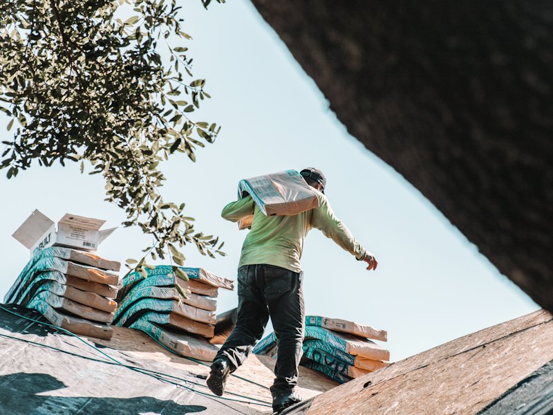 Roofer carrying shingles across a roof
